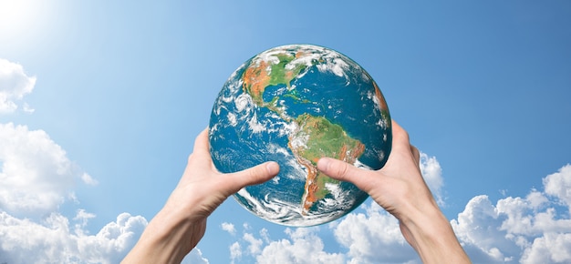 Hands holding a planet, earth on a background of nature blue sky with beautiful white clouds and sunlight.Sustain earth concept. Elements of this image furnished 