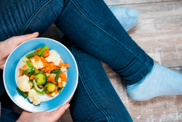 Hands holding a plate of vegetables