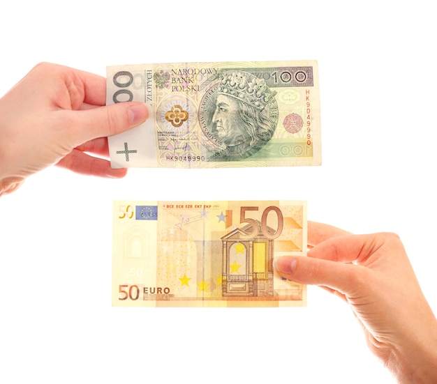 hands holding Polish hundred-zloty note and fifty-euro note over white background