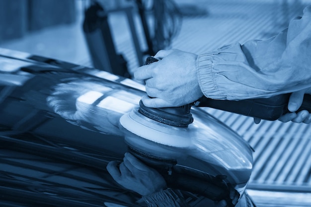 Hands holding polisher to polish car in auto workshop