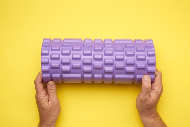 Фото Руки, держащие фиолетовый массажный рулон