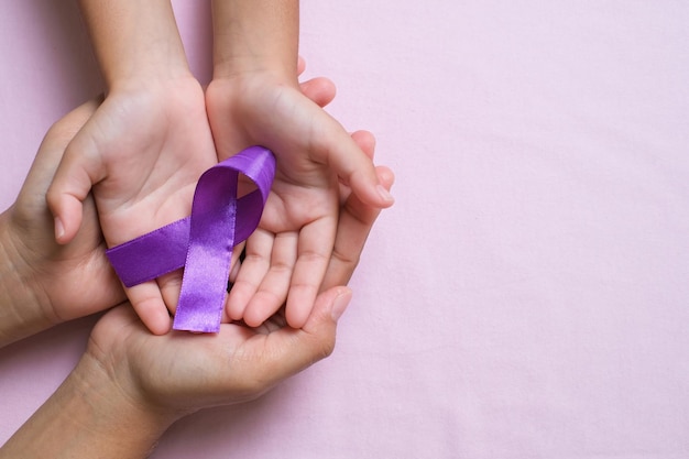 Hands holding Purple ribbons world cancer day concept, Alzheimer disease, Pancreatic cancer, Epilepsy awareness, domestic violence awareness, fibromyalgia awareness