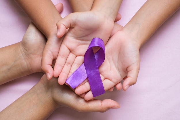 Hands holding purple ribbons world cancer day concept,\
alzheimer disease, pancreatic cancer, epilepsy awareness, domestic\
violence awareness, fibromyalgia awareness