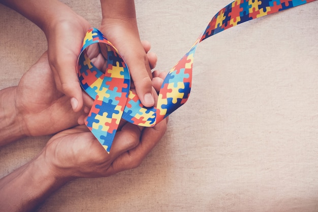 Hands holding puzzle ribbon for autism awareness