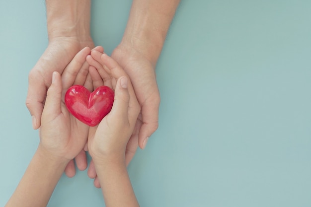 Mani che tengono cuore rosso, concetto di assicurazione sanitaria familiare, giornata mondiale del cuore