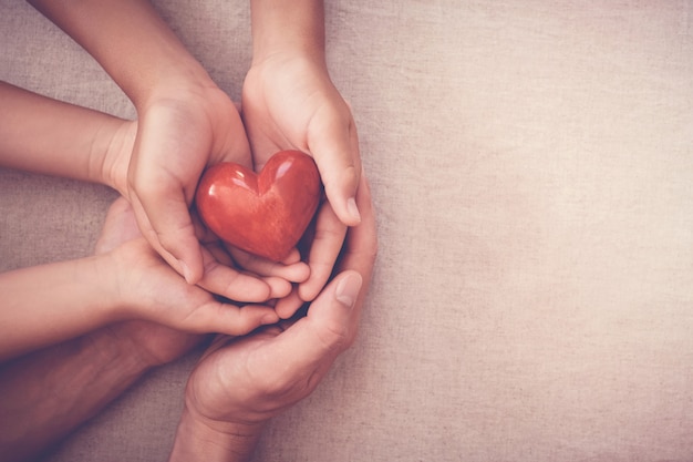 Foto mani che tengono cuore rosso, assicurazione sanitaria, concetto di donazione