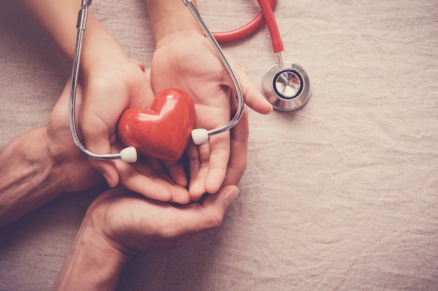 Photo hands holding red heart with stethoscope, heart health, health insurance concept