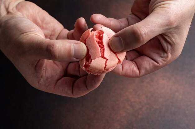 Foto mani che tengono un macaron rosso