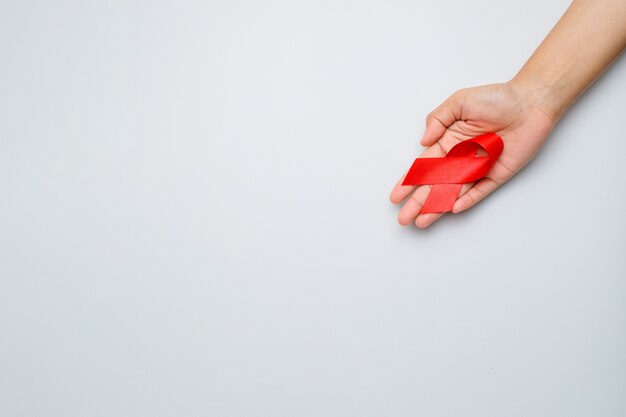 Mani che tengono nastro rosso, concetto di consapevolezza dell'hiv, giornata mondiale dell'aids, giornata mondiale dell'ipertensione