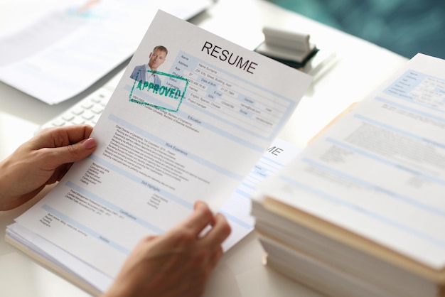 Hands holding resume of man for employment with stamp approved closeup