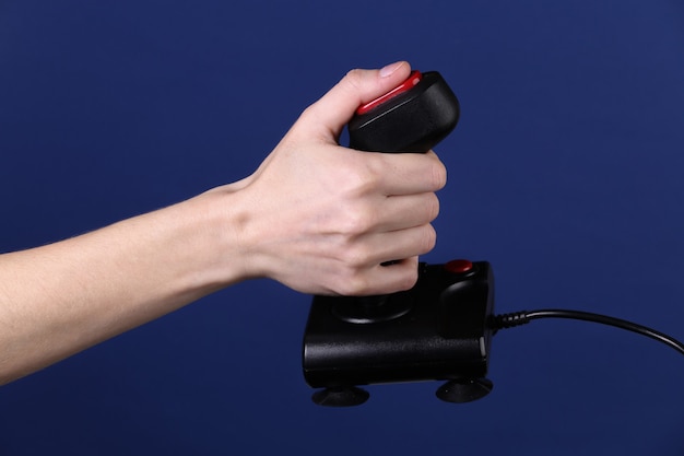 Hands holding retro joystick on classic blue background. Old gaming. 80s retro wave