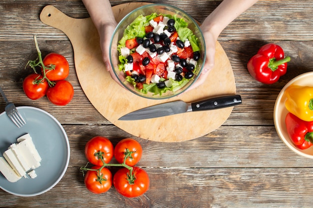 Mani che tengono un'insalata in una ciotola di vetro