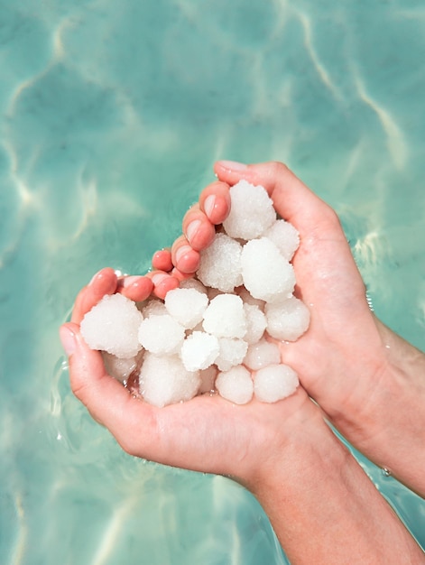 Hands holding sea salt crystals heartsaped on sea water background