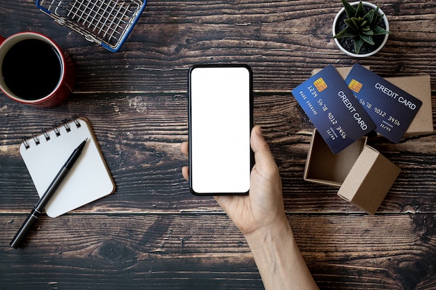 Hands holding a smartphone on a wooden table to shop online