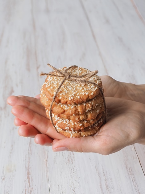 Hands holding a stack of fresh sesame cookies