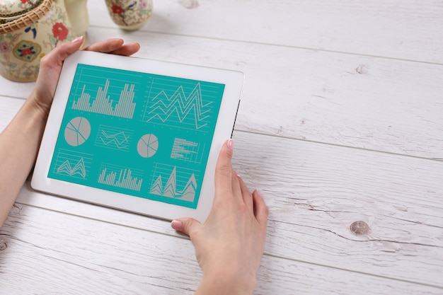 Photo hands holding a tablet lying on the wooden table