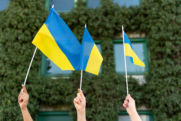 Photo hands holding ukrainian flags outdoors