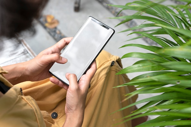 hands holding and using mobile phone with blank screen in garden.