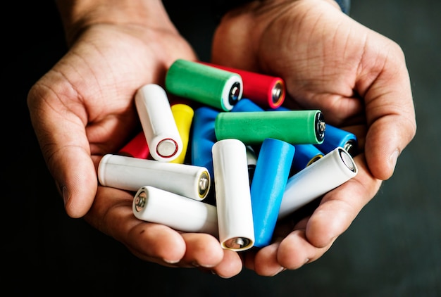 Hands holding various alkaline battery