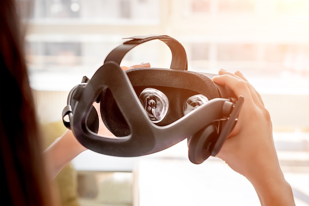 仮想現実ヘルメットを保持している手。将来の仮想ビジュアルのコンセプト、ゲームまたはVRテクノロジーのビデオ