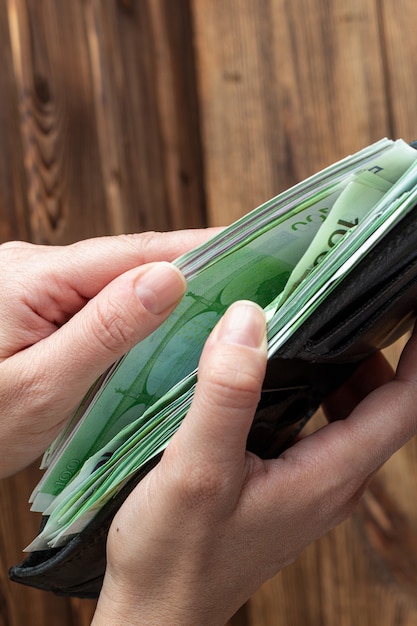 Hands holding wallet full of money banknotes on wooden