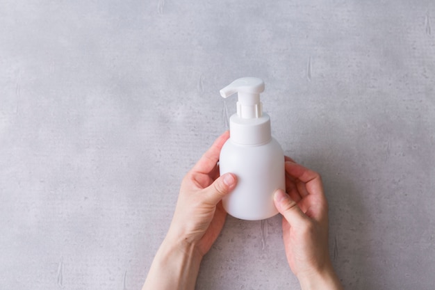 Hands holding a white bottle