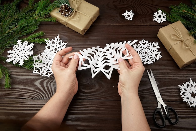 Hands holding white cutted paper snowflake on wooden table