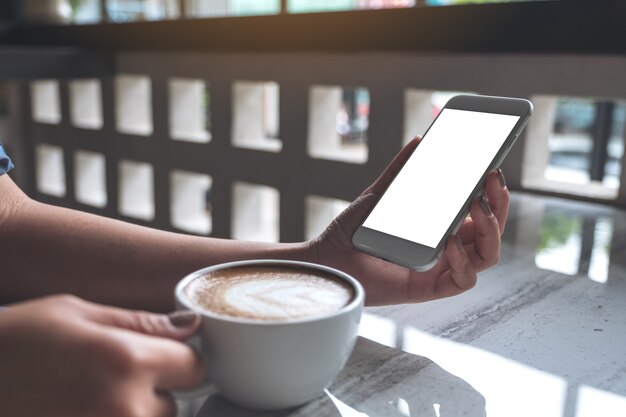 Hands holding white mobile phone with blank desktop screen