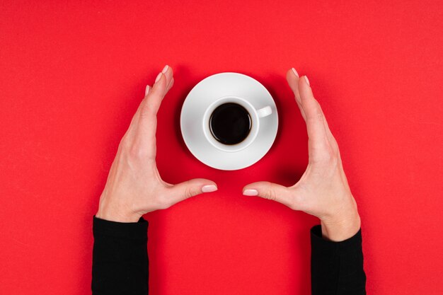 Hands holds a cup of coffee isolated on red