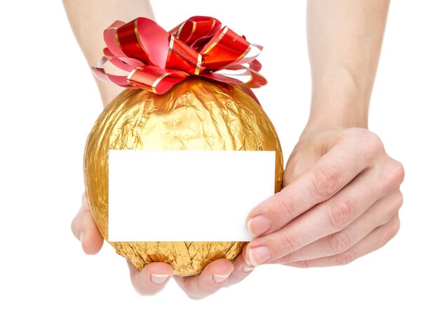 Hands holds round golden gift with bow and empty business card Isolated on white Copy space Greeting card