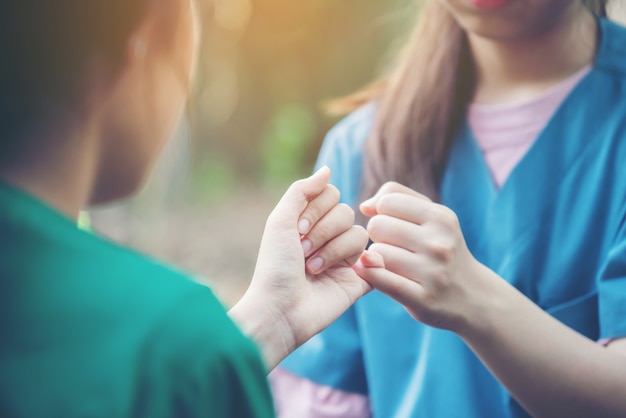 手が自然の背景にお互いの小指を引っ掛ける