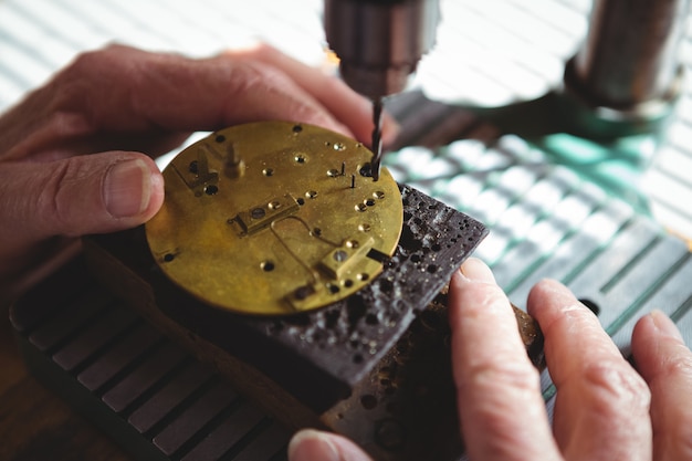 Mani dell'orologista che perforano una quadrante