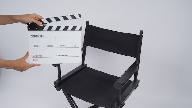 Hands houdt Clapperboard of filmlei vast met zwarte regisseursstoel. het gebruikt in videoproductie, film, bioscoopindustrie op witte achtergrond.