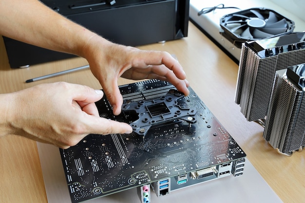 Photo hands install backplate on back of motherboard for fastening cooler processor