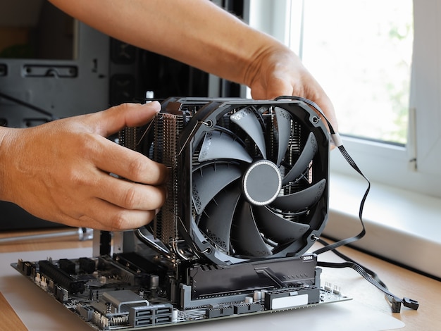 Hands install fans on processor cooling cooler on new motherboard