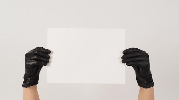 Hands is holding the A4 paper and wear latex glove on white background