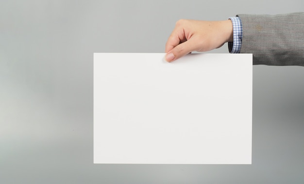 Photo hands is holding board white paper on gray background.wear grey suit.businessman concept.