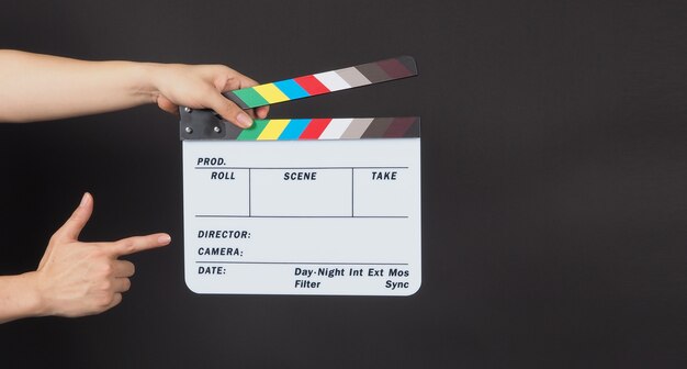 Hands is holding Clapperboard or movie slate. it is used in video production on black background.