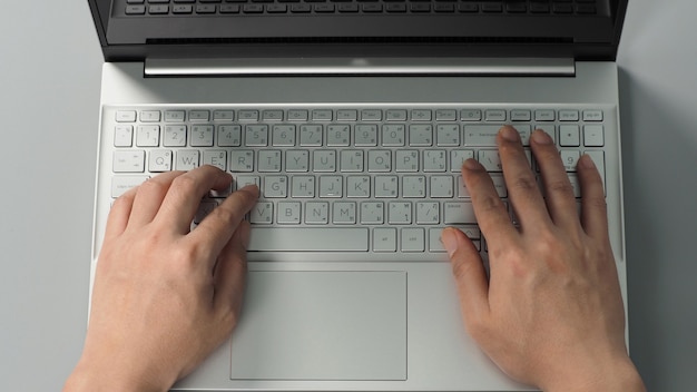 Foto le mani sta digitando sul computer portatile o notebook su sfondo grigio. studio shot.top vista dell'occhio.