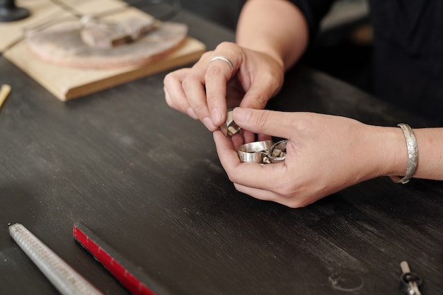 Photo hands of jeweler checking silver rings while making it in own workshop