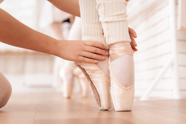 Hands of Kid Legs of Ballerina in Pointe Shoes.