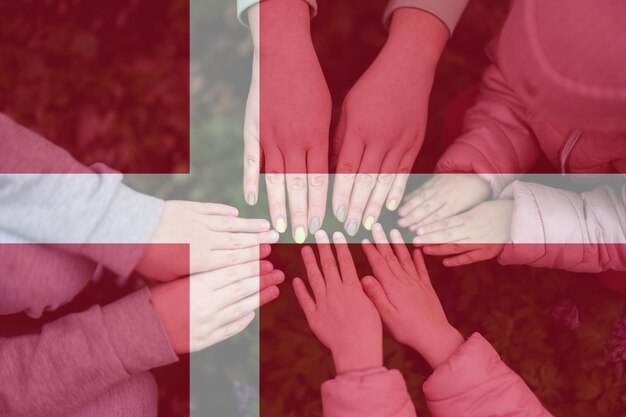 Hands of kids on background of Denmark flag Danish patriotism and unity concept