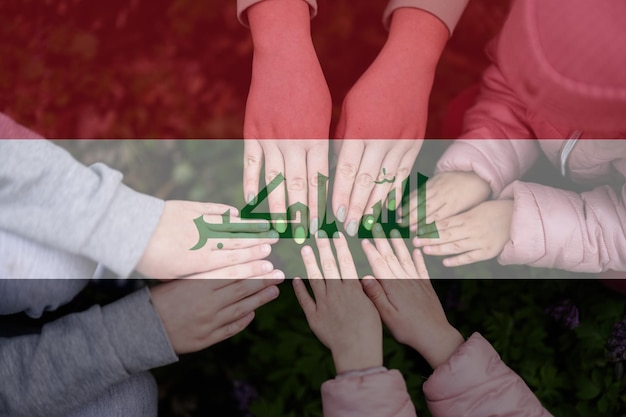 Hands of kids on background of Iraq flag Iraqi patriotism and unity concept