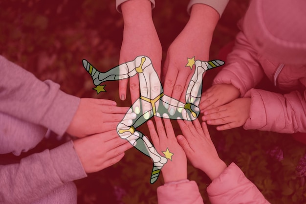 Hands of kids on background of Isle of Man flag Manx patriotism and unity concept