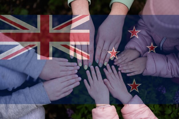 Hands of kids on background of New Zealand flag New Zealander patriotism and unity concept