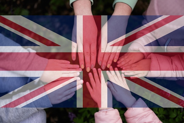 Hands of kids on background of United Kingdom flag British patriotism and unity concept