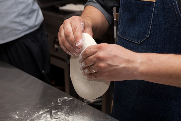 Hands knead dough for pizza or focaccia