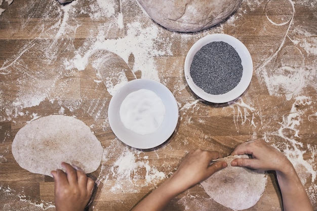 Foto mani che impastano la pasta persone che fanno la pasta per il pane durante il laboratorio di produzione del pane farina e pasta