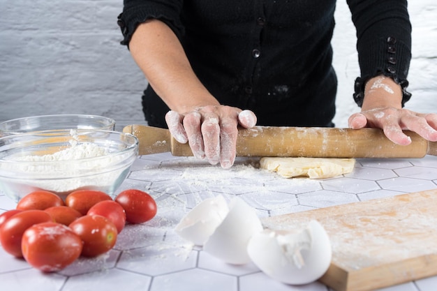 Hands kneading with ingredients and kitchen tools around