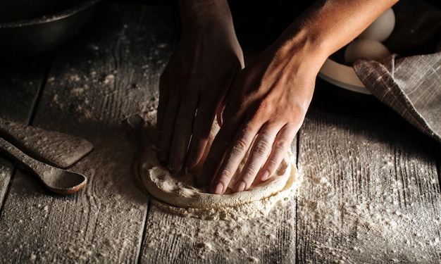 Foto mani che impastano un impasto per la cottura della pizza con la farina